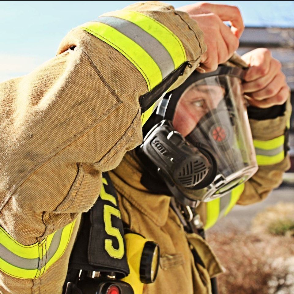Firefighter putting breathing apparatus on his face