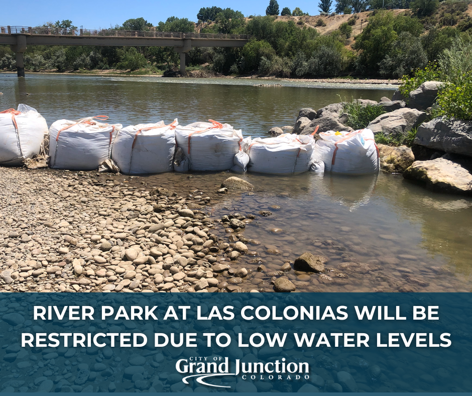 A low water level river with sand bags at the entrance. 