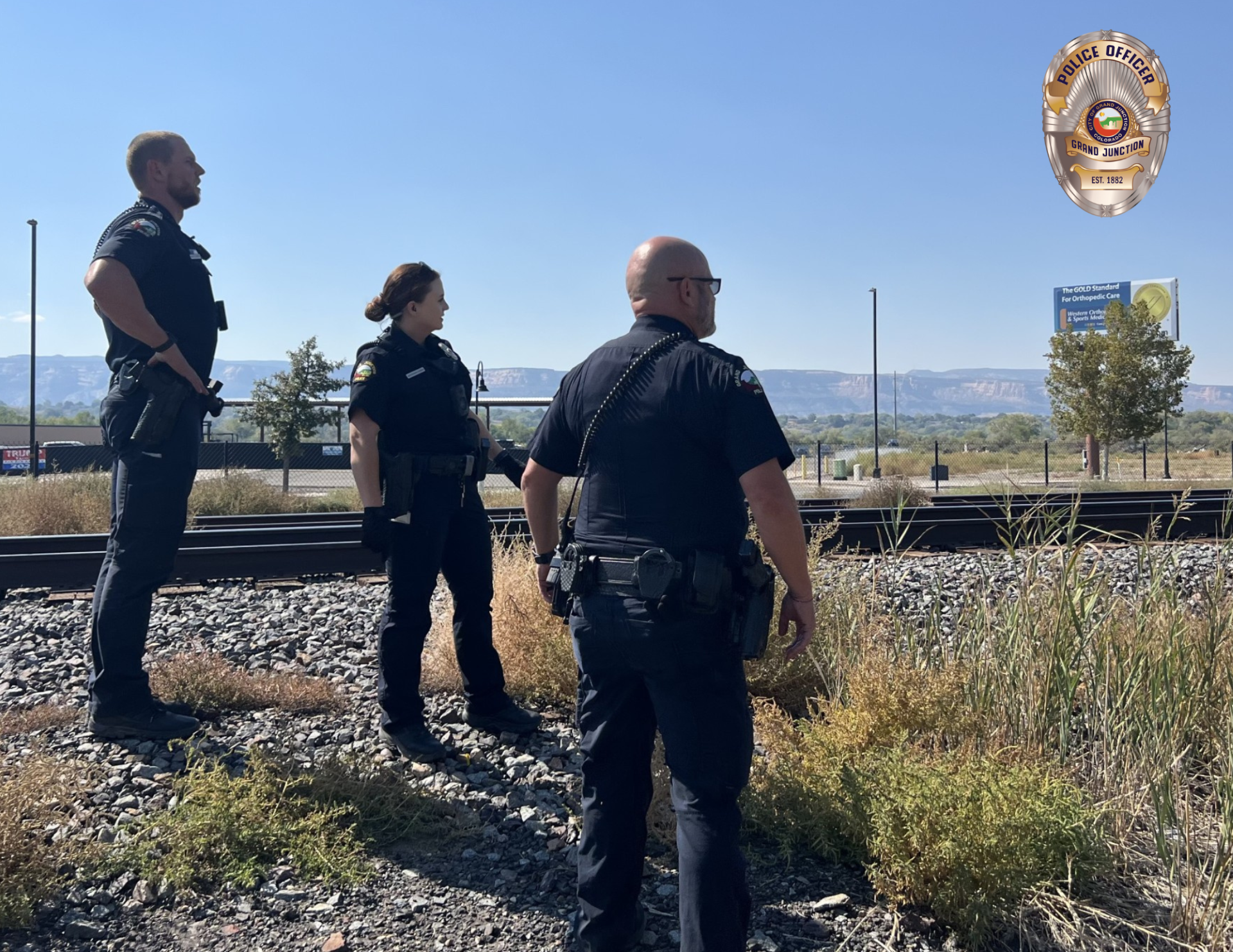 Three officers looking down a railroad track