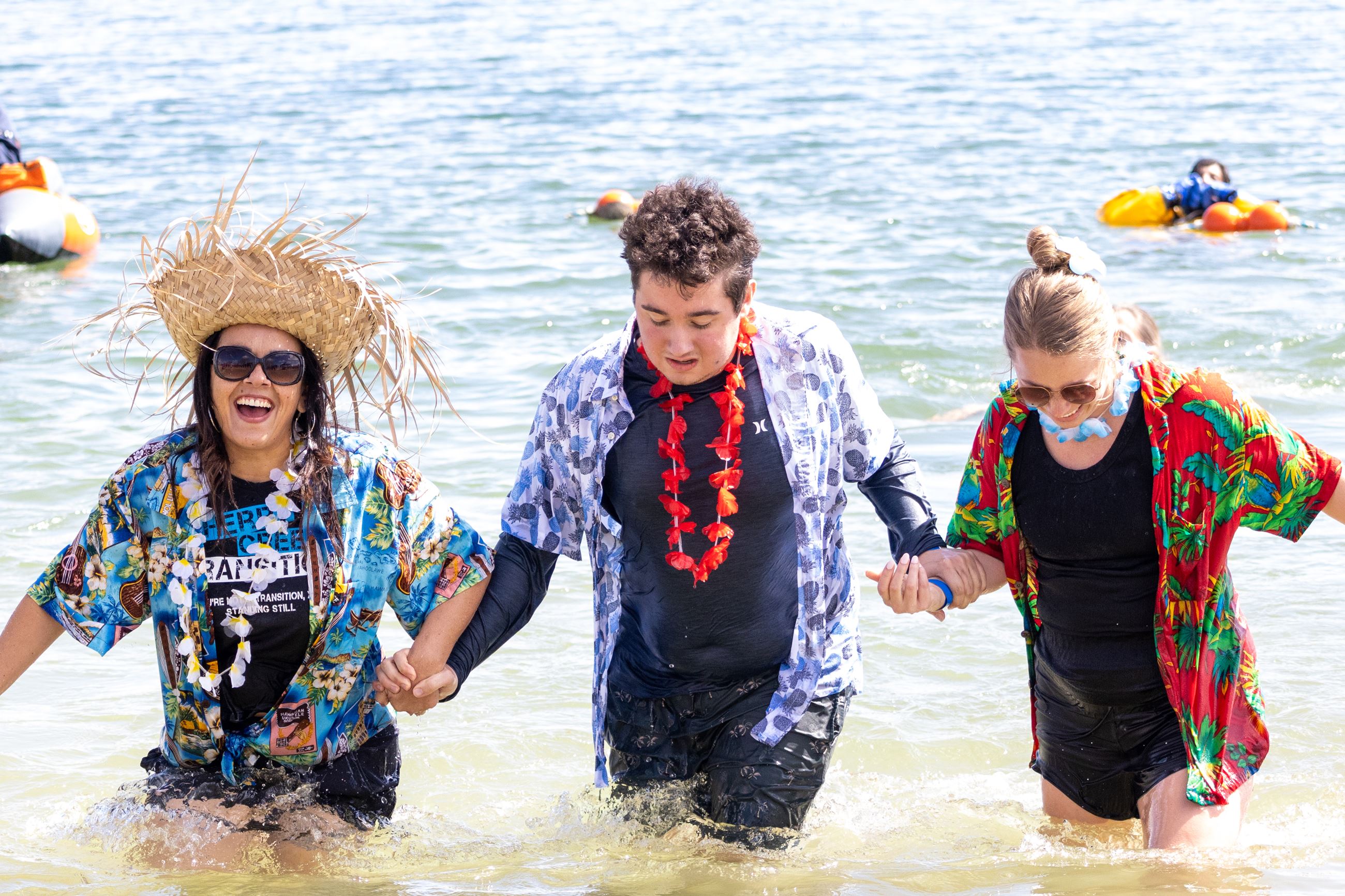 Three people in tropical shirts walking out of a cold lake